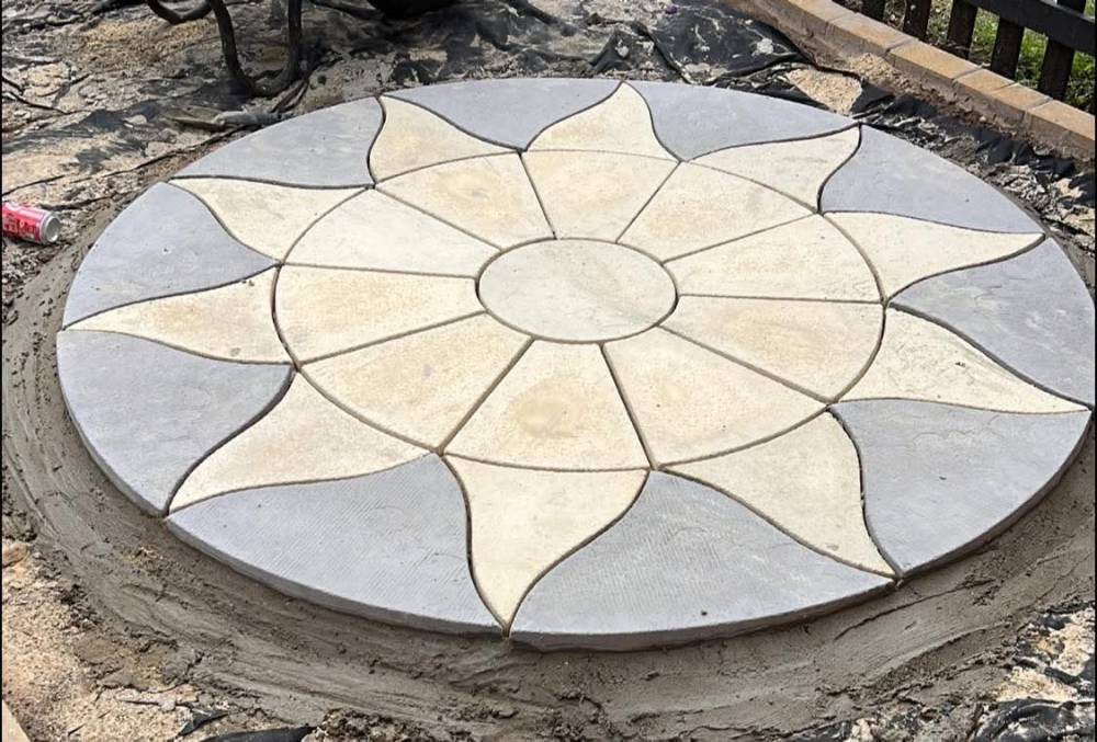 A sun-pattern patio circle being laid